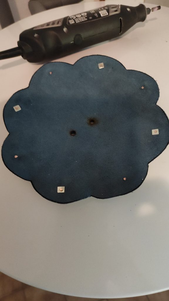 the back of a flower shaped roundel spaulder, showing the rivets on the leather backing