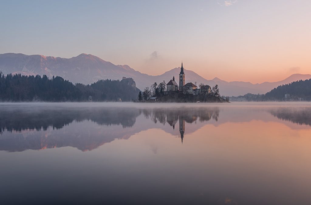a landscape in the mist showing an abbey on a small island in a lake
